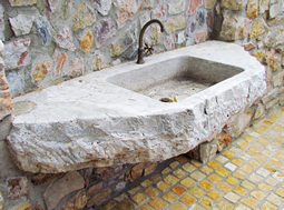 Antique reclaimed stone basin sink salvaged restored and installed in this traditional style Mediterranean home.